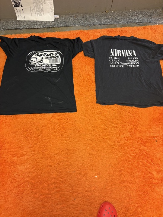 High Steppin' Seafood sardine-can t-shirt photographed next to an original early-1990s Nirvana t-shirt on an orange rug
