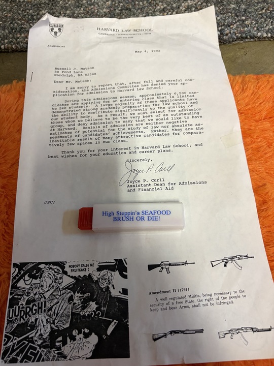 White band toothbrush printed with High Steppin' Seafood - BRUSH OR DIE!, resting on the Harvard rejection letter